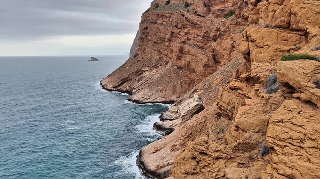 A truly spectacular coastal scenery showcases rugged cliffs alongside serene waters beneath expansive gray skies