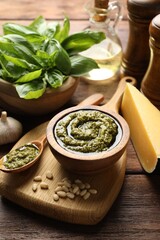 Fresh pesto sauce and ingredients on wooden table, closeup