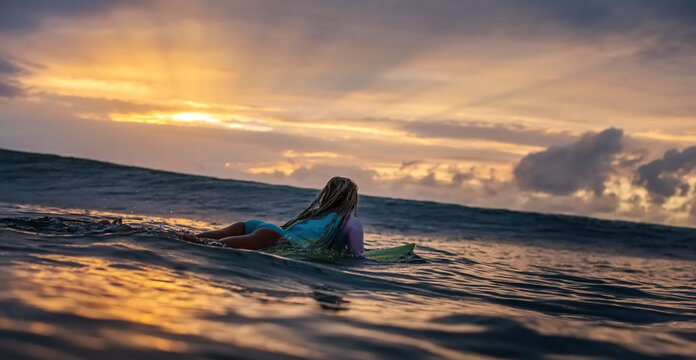 Surfing Girl in sunset sea waiting for the right wave