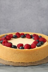 Delicious cheesecake with fresh berries on grey wooden table, closeup