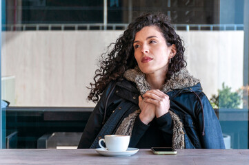 Thoughtful woman with coffee cup in urban café setting
