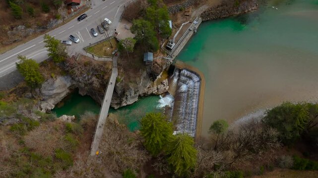 A breathtaking aerial view of Lechfall in Fussen, Germany. The turquoise waters cascade over the dam, surrounded by rugged cliffs and lush forests. A must-visit natural wonder in the Bavarian Alps
