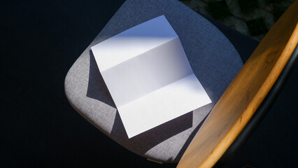 plain trifold brochure paper on the fabric chair background