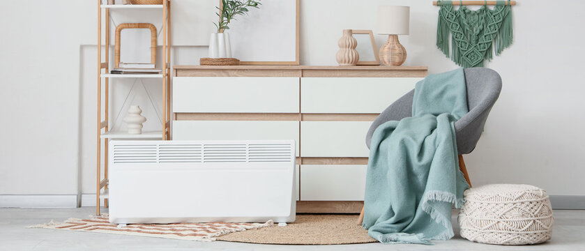 Interior of light room with drawers, shelf unit and electric convector heater