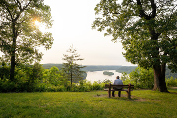 Man sitting at overlook by the lake in summer