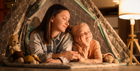 Cute little girl with her mother lying in play tent at home © Pixel-Shot