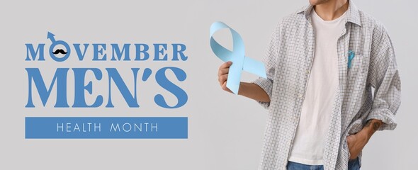 Young man with blue awareness ribbons on light background. Movember - men's health month