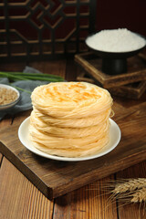 Traditional Chinese Layered Pancakes Stack on Rustic Wooden Board with Asian Kitchen Setup