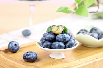 Fresh Blueberries on White Stand with Cut Fruit Showing Flesh on Wooden Board