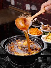 Traditional Chinese Hot Pot with Wooden Ladle and Colorful Spice Ingredients