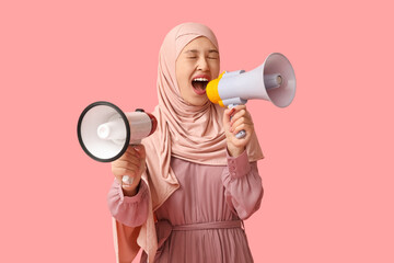 Young Asian Muslim woman shouting into megaphones on pink background. National Be Heard Day