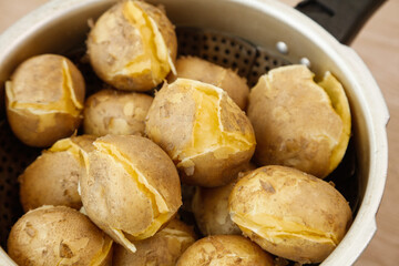 Steamed Potatoes with Bursting Golden Skins in Kitchen Basket Closeup