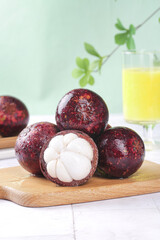 Fresh Mangosteen Tropical Fruit from Yunnan China on Wooden Board with Orange Juice