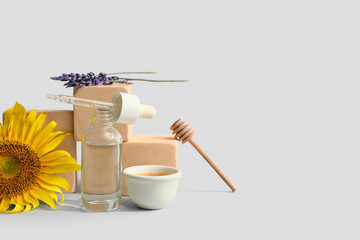 Composition with bottle of cosmetic product, honey and sunflower on light background