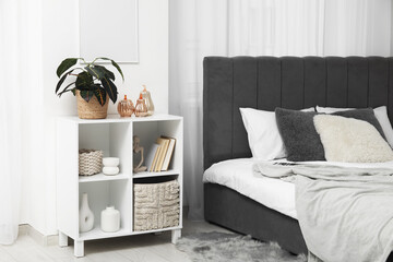 Decorative pumpkins with plant on shelf in light bedroom interior