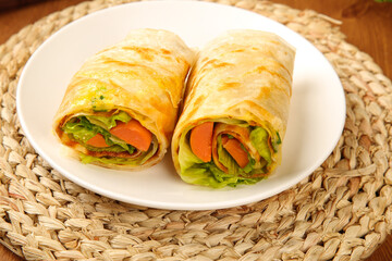 Homemade vegetable wraps with ham and fresh greens on rustic wicker placemat healthy lunch meal