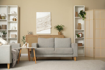Fototapeta premium Interior of stylish modern living room with grey sofas, coffee table and shelving units