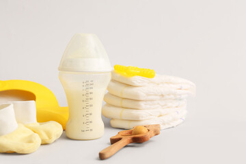 Bottle with baby milk formula and different accessories on light background