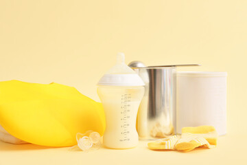 Bottle with baby milk formula, socks, pacifier and bib on color background