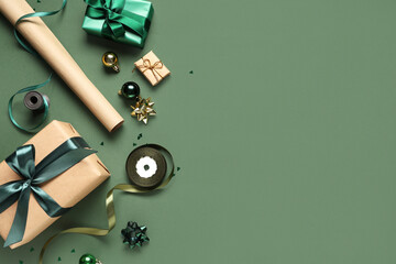 Christmas gift boxes with packing materials and different decorations on green background