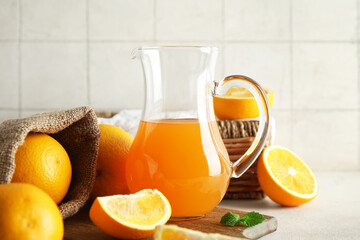 Jug of fresh orange juice and sack bag with fruits on white table