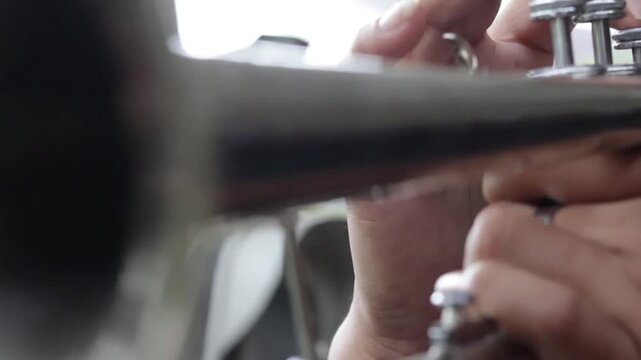 Close-up of fingers moving on trumpet valves during a performance, perfect for jazz and orchestral themes.