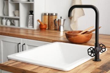Sink on wooden counter near white wall in comfortable kitchen