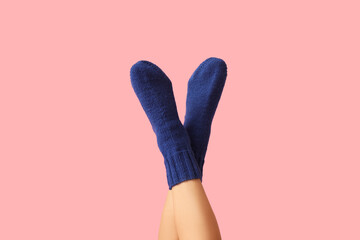 Legs of young woman in blue knitted socks on pink background