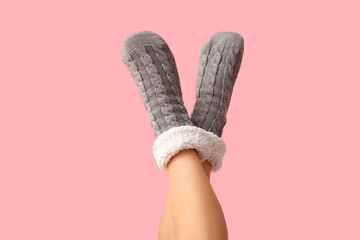Legs of young woman in grey warm socks on pink background