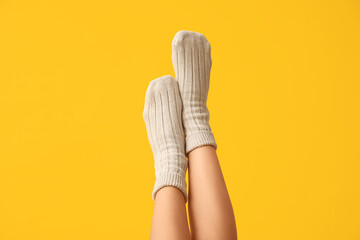 Legs of young woman in cotton socks on yellow background