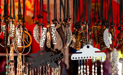 Handmade artisan necklaces hanging in a colorful market stall, featuring carved pendants, beads and ethnic jewelry details. Perfect for concepts of culture, crafts and souvenirs.