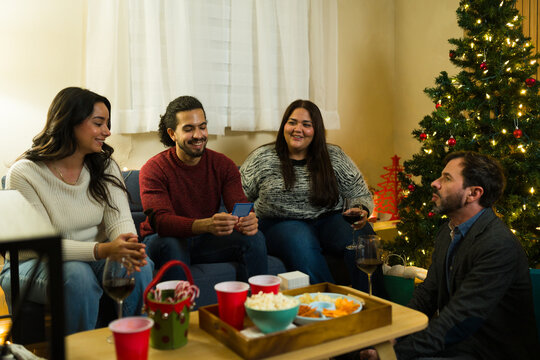 Group of friends playing a card game and celebrating christmas holiday reunion at home - Powered by Adobe
