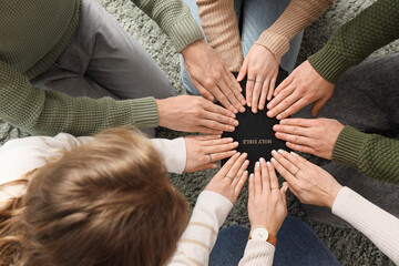 Obraz premium Group of people praying with Holy Bible on carpet, top view