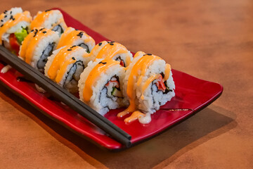 Close up view of Kani Sushi on the long red plate with black chopsticks. Wooden table. beautifully arranged. sushi roll filled with a variety of fresh ingredients, showcasing the artistry of Japanese.