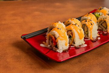 Close up view of Kani Sushi on the long red plate with black chopsticks. Wooden table. beautifully arranged. sushi roll filled with a variety of fresh ingredients, showcasing the artistry of Japanese.