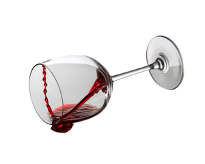 Dramatic red wine spill in a tilted glass on black background with vibrant color and detailed textures