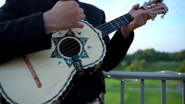 Musician playing the traditional string instrument, mariachi band, wearing a dark suit with decorative details