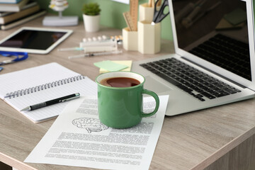 Cup of coffee with study materials on medical student's table in office, closeup