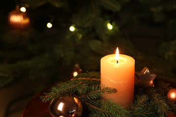 Composition with burning candle, fir branches and decorations near Christmas tree indoors