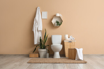 Interior of restroom with toilet bowl, basket and bathrobe