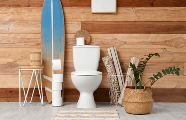 Interior of restroom with toilet bowl, table and surfboard