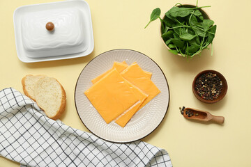 Plates of tasty processed cheese with spinach, bread and bowl of peppercorns on beige background. Top view