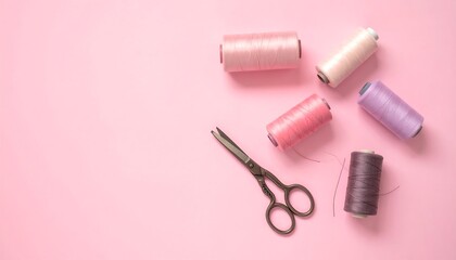 Overhead shot of pink background with five thread spools in various colors and a pair of small scissors, evoking crafts