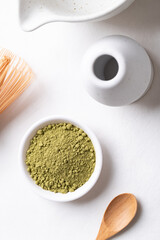 Top view of matcha green tea powder with bamboo whisk and bowl on white background