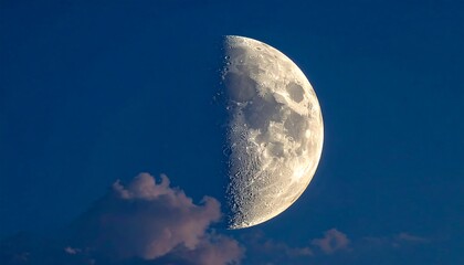 A close-up of a bright, half-illuminated lunar body set against a deep blue evening sky