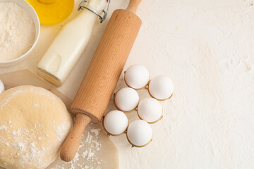 Wooden rolling pin, dough and ingredients on white background