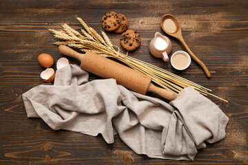 Composition with rolling pin and ingredients for dough on wooden background