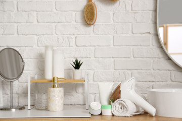 Modern photoepilator with towel and cosmetic products near sink in bathroom