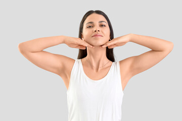 Fototapeta premium Young woman doing face building exercise on light background