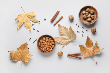 Composition with almond nuts, spices, acorns and fallen leaves on grey background